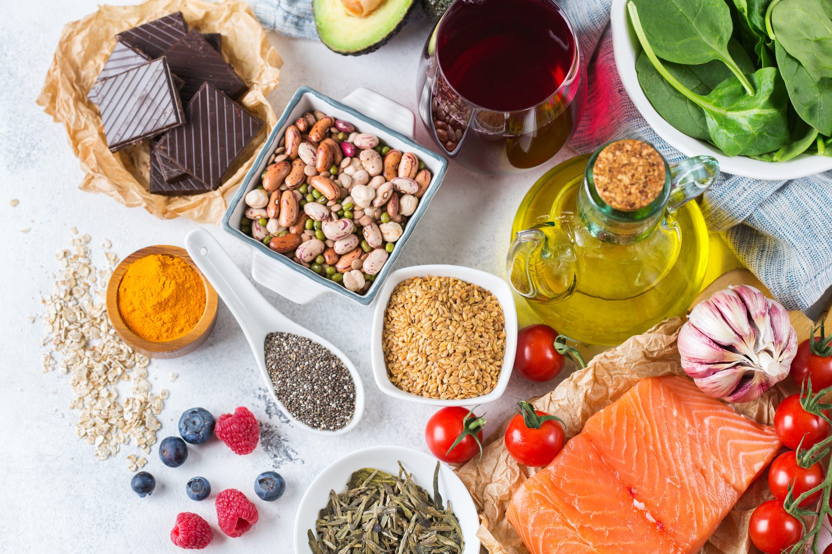 Assortment of heart-healthy foods including oily fish, nuts, avocado and olive oil
